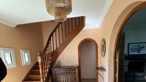 Una escalera con barandilla de madera, una lámpara de fibra y un tapete en el suelo.