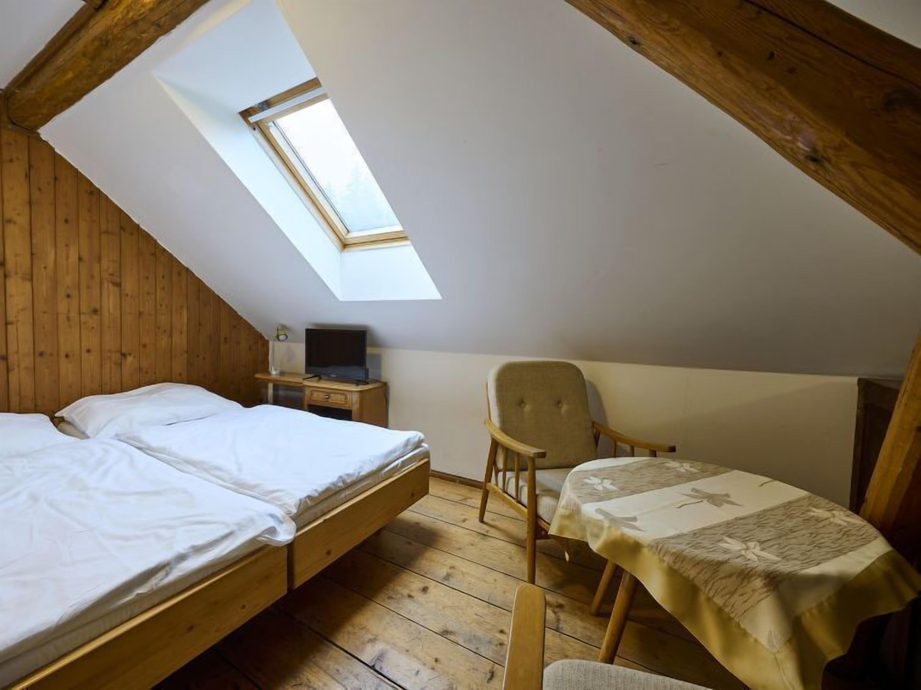 A bedroom with two beds, a desk, a chair, and a skylight.