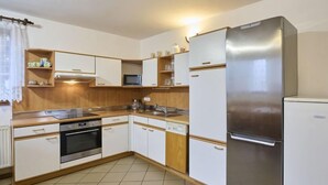 A compact kitchen with white cabinets, a stainless steel refrigerator, a microwave, and a stove. - Garden & Pets Escape by Interhome (Tanvald)
