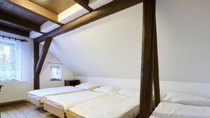 A room with three wooden beds aligned against a white wall, under a sloped ceiling with exposed beams. - Garden & Pets Escape by Interhome (Tanvald)
