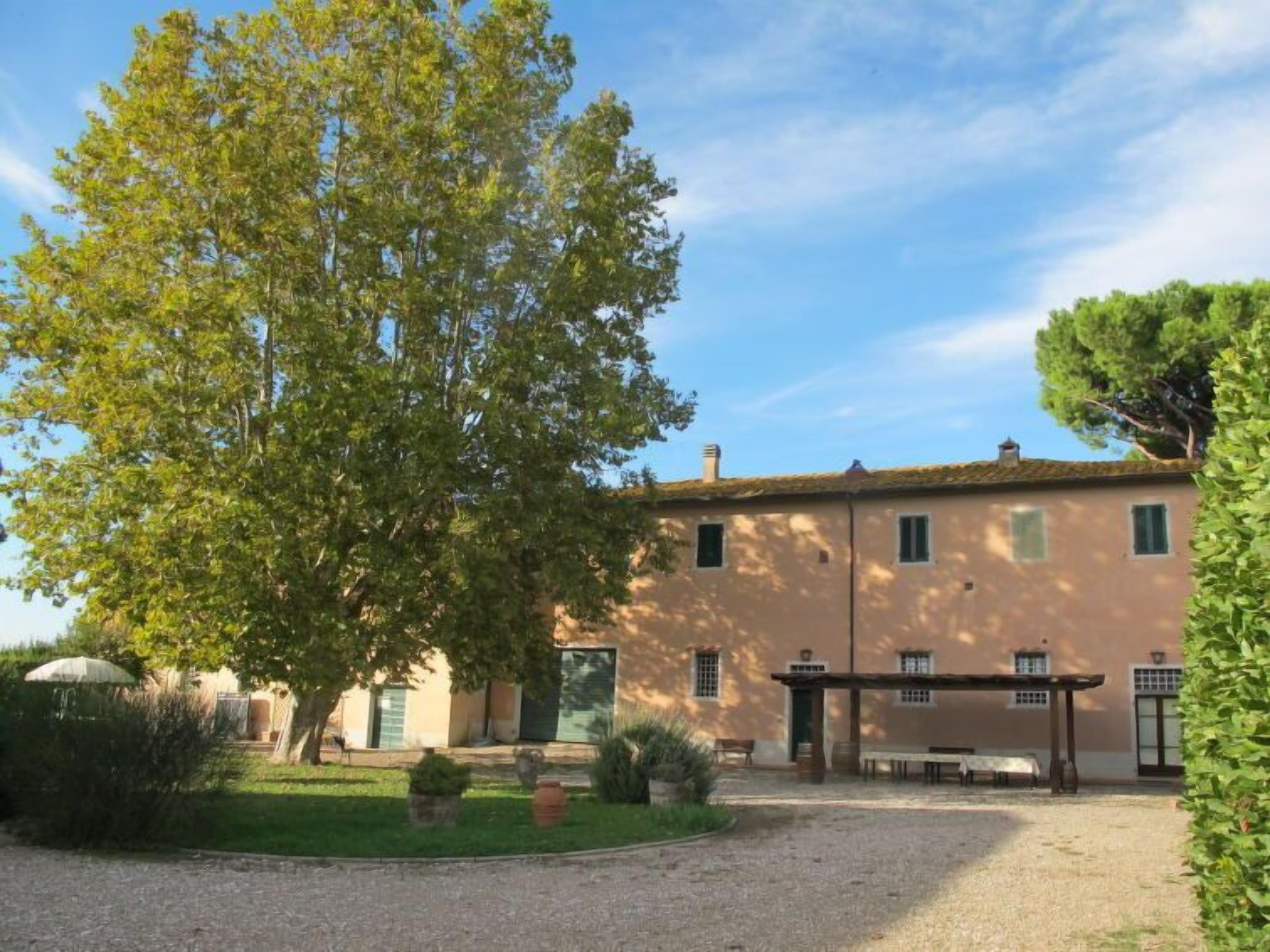 Un bâtiment doté d’un jardin, d’une pergola et d’un chemin de gravier.