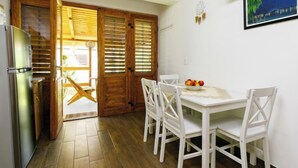 Eine kleine Küche mit Kühlschrank, Holztüren und einem Esstisch mit Stühlen.