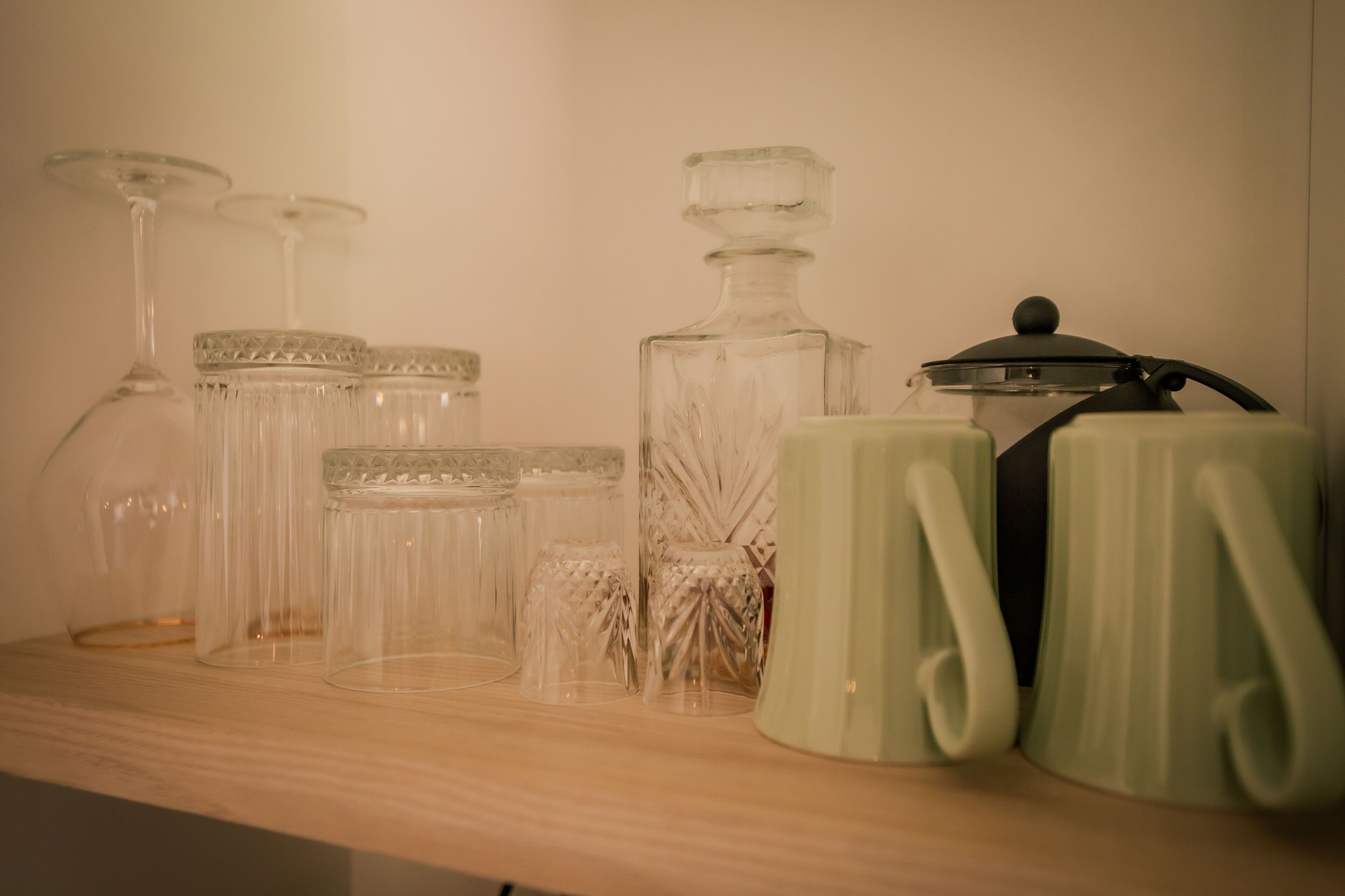 A shelf with various glass containers and a green mug.