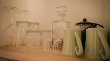 A shelf with various glass containers and a green mug.