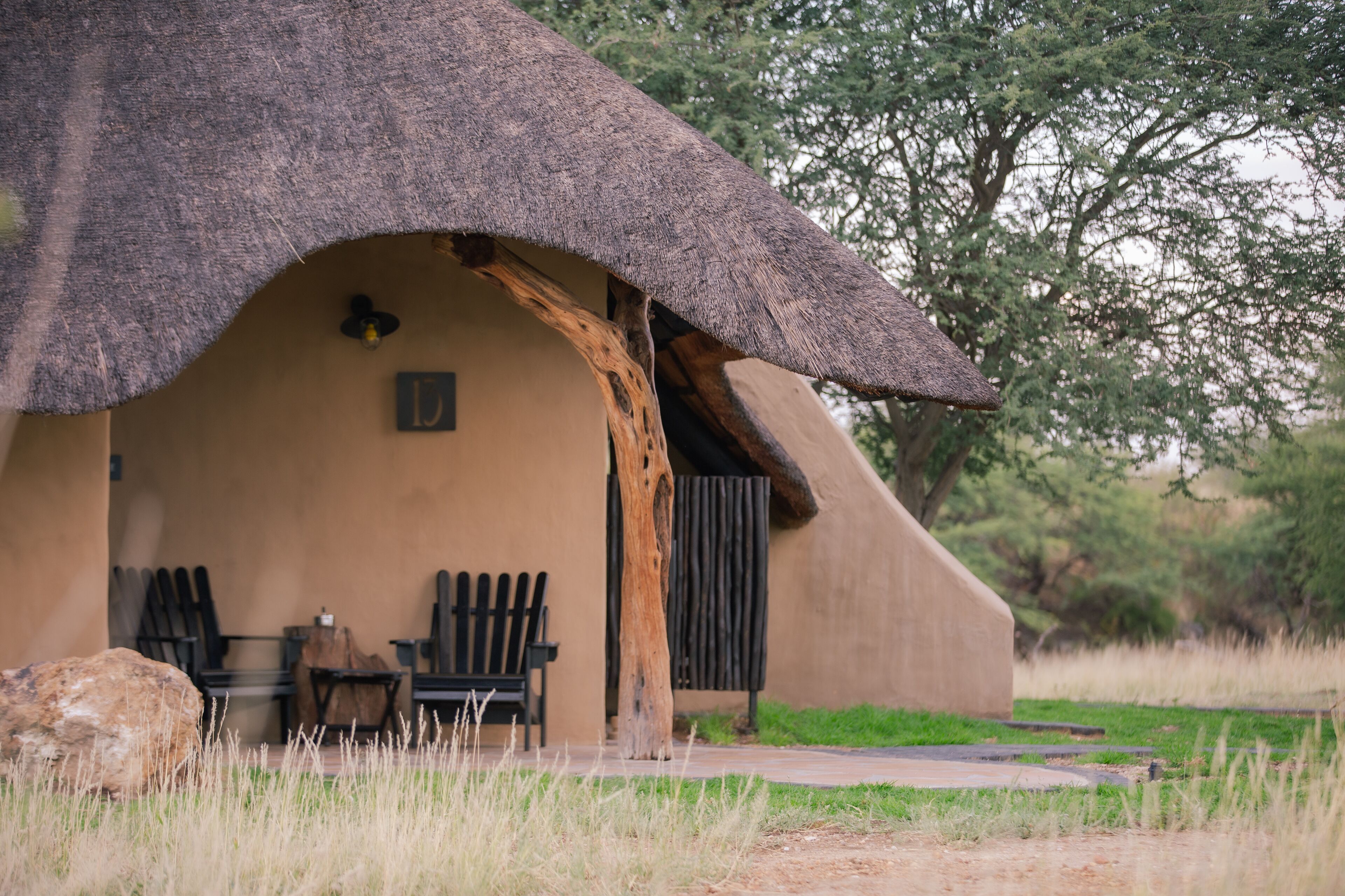 A thatched-roof hut with a bench and a table outside.
