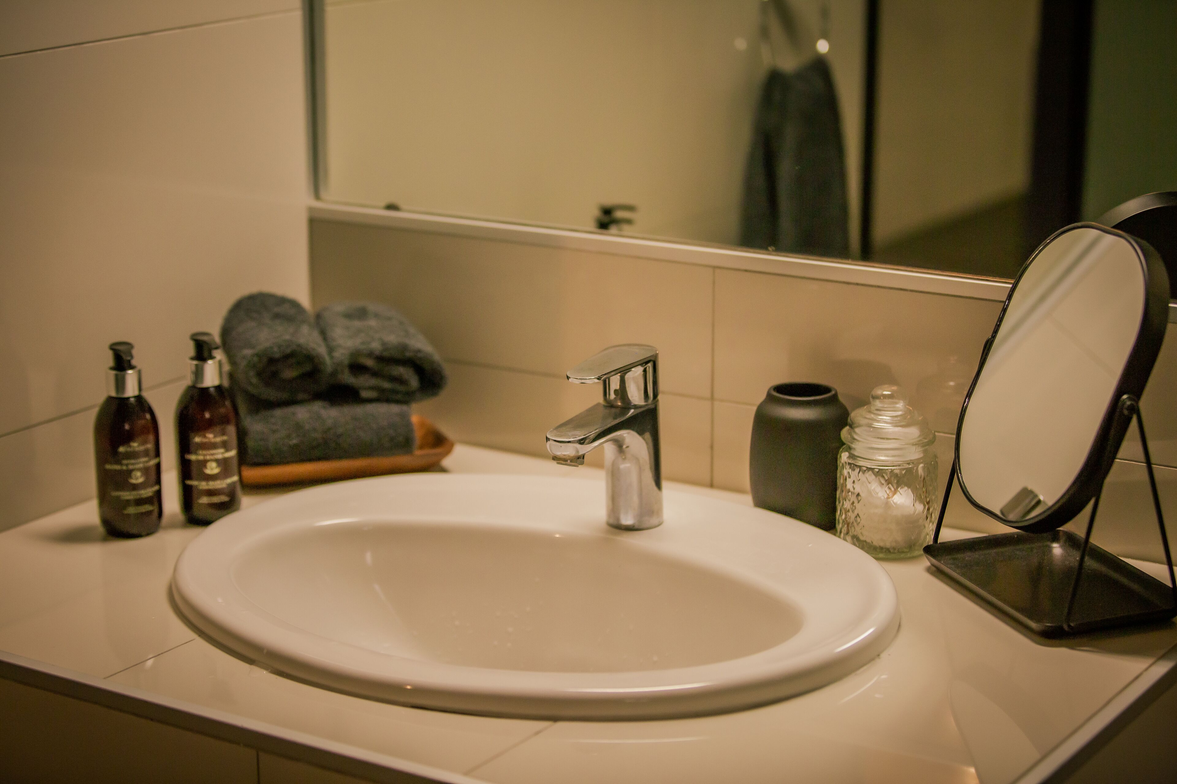 Un lavabo con espejo, dos botellas y una toalla.