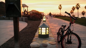 A bicycle parked next to a stone pillar with a lit lantern, a pet waste pick-up mitt sign, and a gazebo in the background. - Ocean Mist: Chef's Kitchen & Private Pool (Pompano Beach)