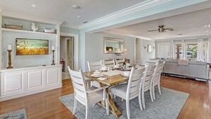 A dining area with a wooden table set for six, surrounded by white chairs. - Ocean Mist: Chef's Kitchen & Private Pool (Pompano Beach)