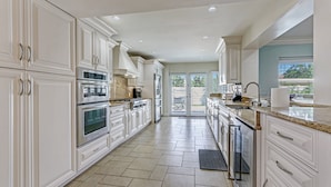 A spacious kitchen with white cabinetry, stainless steel appliances, and a large window providing natural light. - Ocean Mist: Chef's Kitchen & Private Pool (Pompano Beach)