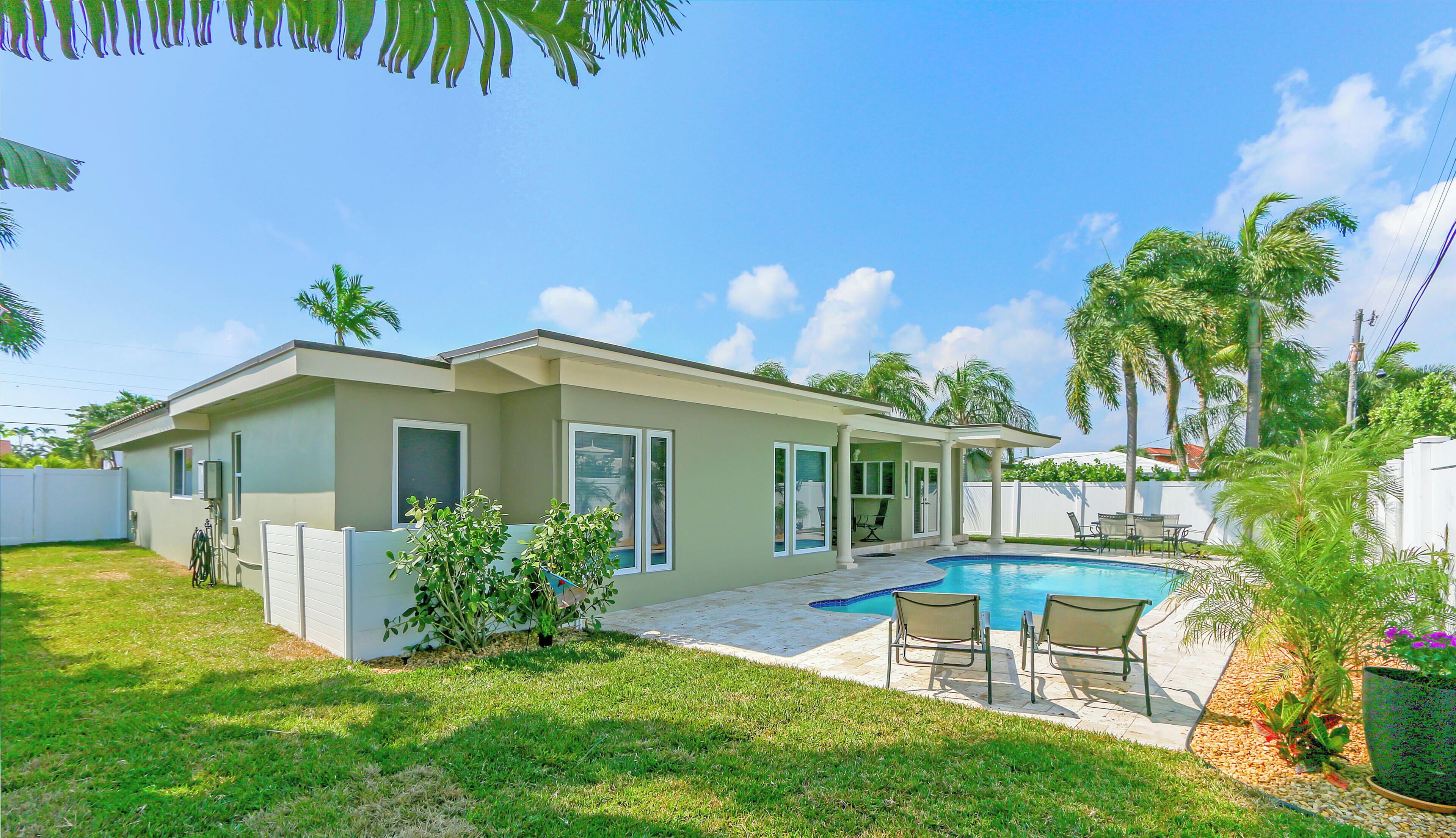 A modern house with a swimming pool, a covered patio, and a well-maintained lawn.