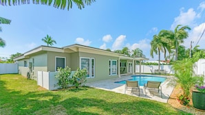 A modern house with a swimming pool, a covered patio, and a well-maintained lawn. - Ocean Mist: Chef's Kitchen & Private Pool (Pompano Beach)