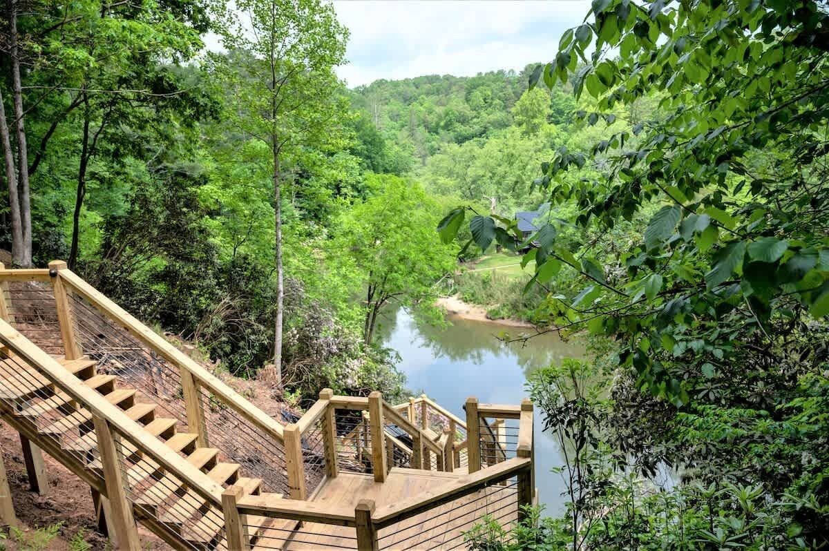 Eine Holztreppe führt zu einem Fluss, der von dichtem Grün umgeben ist.