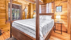 Un dormitorio de cabaña de madera con una cama con dosel, paredes de madera y una mesita de noche con lámpara.