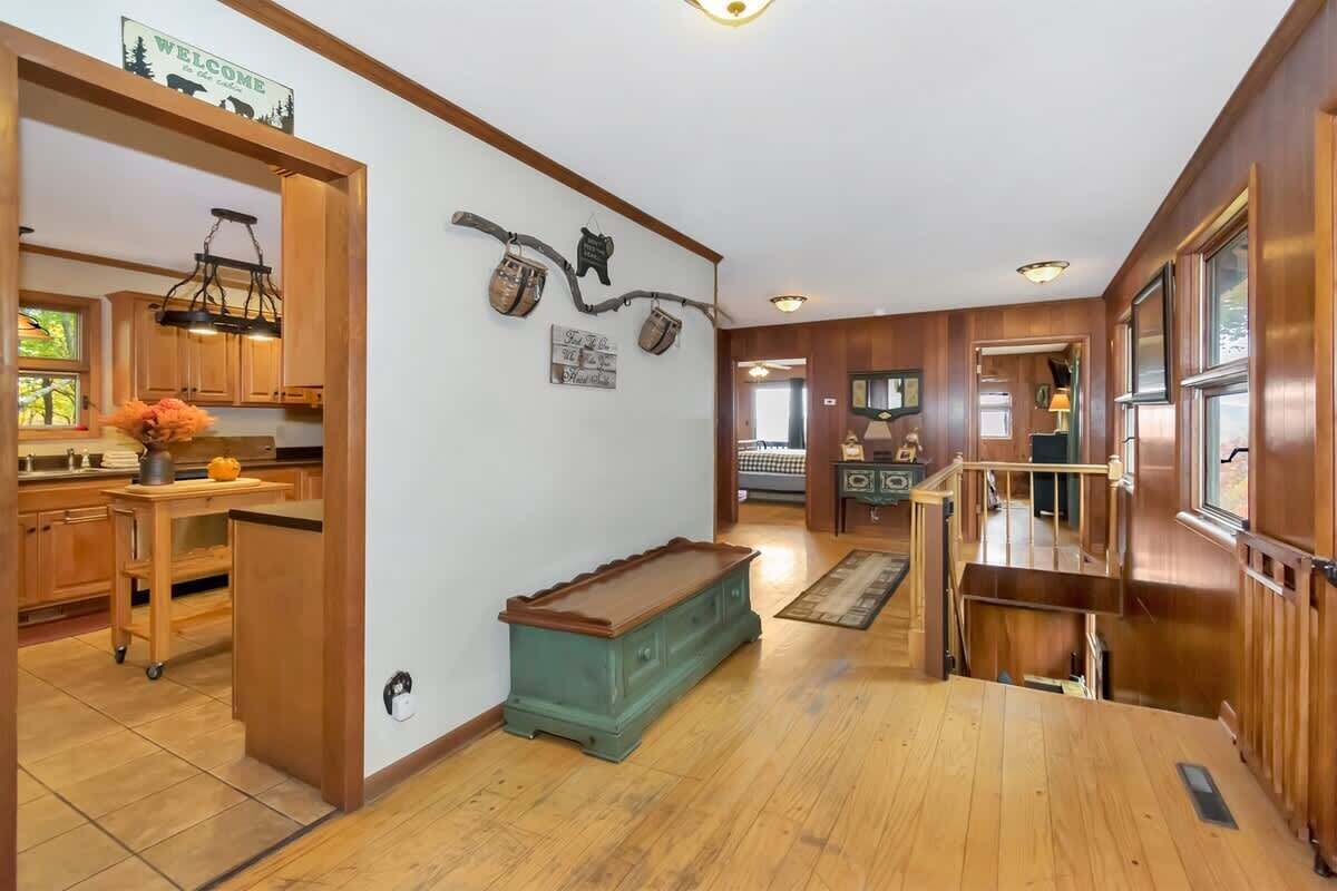A spacious interior with wooden flooring, a kitchen area with wooden cabinets, a bench, and a staircase leading to another level.