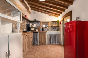 A compact kitchen with wooden cabinets, a red refrigerator, and a tiled backsplash.