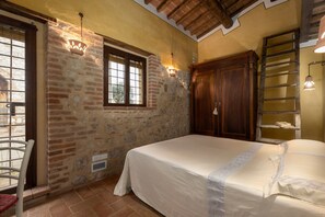 A bedroom with a bed, a window, a chair, and a wooden wardrobe.