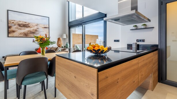 Una cucina moderna con isola centrale, zona pranzo con sedie e un'ampia finestra che offre luce naturale.