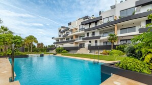 Un moderno edificio residenziale con piscina, balconi e vegetazione lussureggiante.