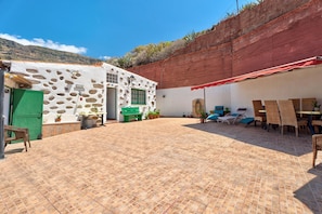 A courtyard with a stone wall, a green door, and a red awning.