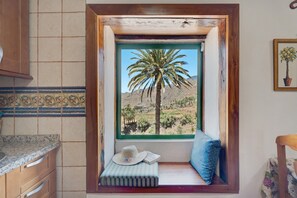 A kitchen with a window seat, a hat, and a book. - Vacation Home "Rosa del Negro" with Sea View, Terrace & Wi-Fi (Alojera)