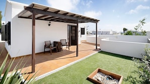 Une terrasse sur le toit, agrémentée d’une pergola, d’une table et de chaises, ainsi que d’un petit espace jardin.