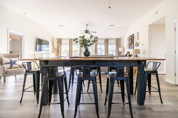 A spacious kitchen with a central island, bar stools, a ceiling fan, and a large window.