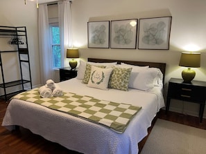 A neatly made bed with a checkered bedspread, two bedside lamps, and a window with curtains.