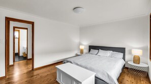 A bedroom with a bed, bedside tables, a mirror, and a ceiling light.
