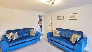 A room with two blue sofas and a door leading to another room. - Host & Stay | Kenmore (Hexham)