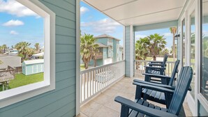 A covered balcony with a view of neighboring houses and palm trees. - Three story townhome. Garage access. Golf cart included. Very short drive to the (Port Aransas)