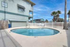 A swimming pool with a 4 FT depth marker, surrounded by a white fence, with a wooden deck and a building in the background. - Three story townhome. Garage access. Golf cart included. Very short drive to the (Port Aransas)