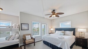 A bedroom with a bunk bed, a single bed, a ceiling fan, and a nightstand with a lamp. - Three story townhome. Garage access. Golf cart included. Very short drive to the (Port Aransas)