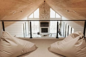 Ein Dachzimmer mit hohen Decken, einer geneigten Zimmerdecke und Blick auf eine Treppe, die in eine untere Ebene führt.