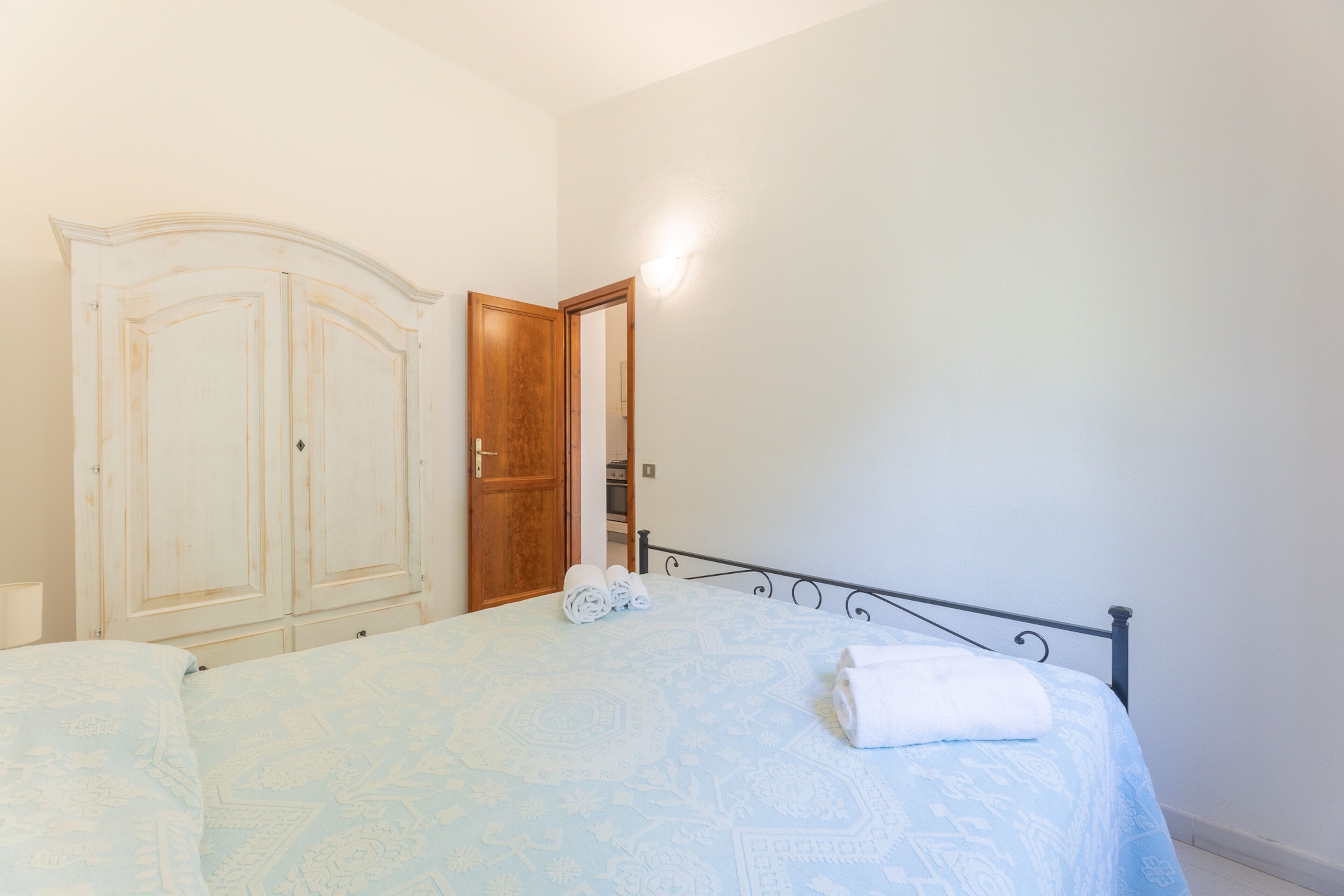 A bedroom with a bed, a wardrobe, and a mirror.