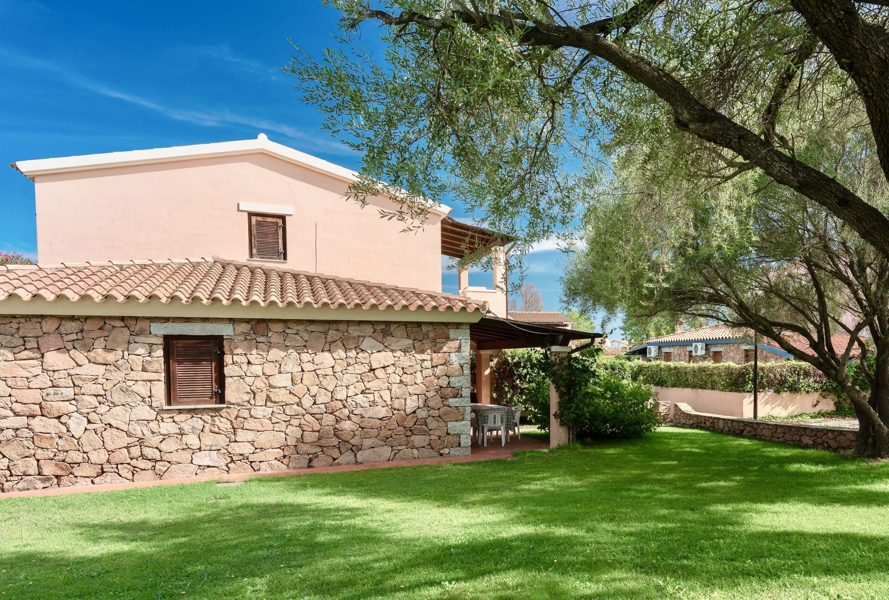 A stone building with a tiled roof, a small window, and a patio area with a table and chairs.