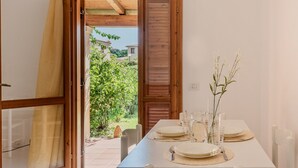 Un coin repas avec une table dressée pour quatre personnes, une porte en bois et une vue sur un jardin.