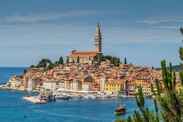 A coastal town with a prominent church and tower, colorful buildings, and a marina with boats.