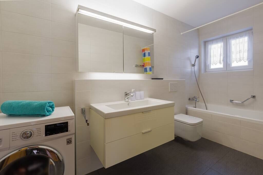 Une salle de bain équipée d’un lave-linge, d’un évier, de toilettes et d’une baignoire.