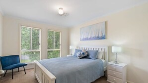 Une chambre à coucher avec un lit, deux tables de chevet, une chaise et une fenêtre.