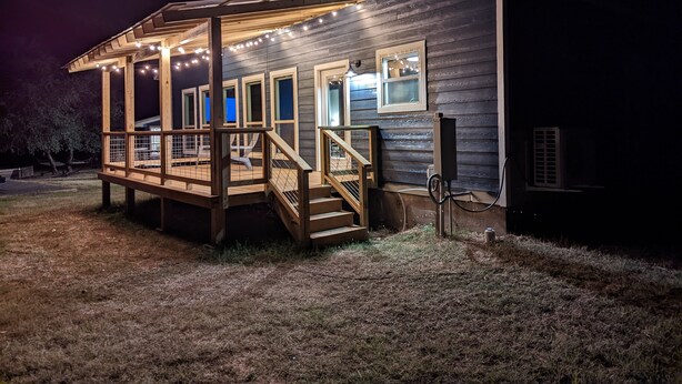 A wooden cabin with a covered porch, multiple windows, and outdoor lighting.