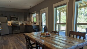 A modern kitchen with dark cabinets, stainless steel appliances, and a wooden dining table with chairs.