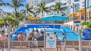 Et vandland med en blå rutsjebane, et skilt der angiver en 'Splash Zone' og en 'FlowRider'-attraktion.