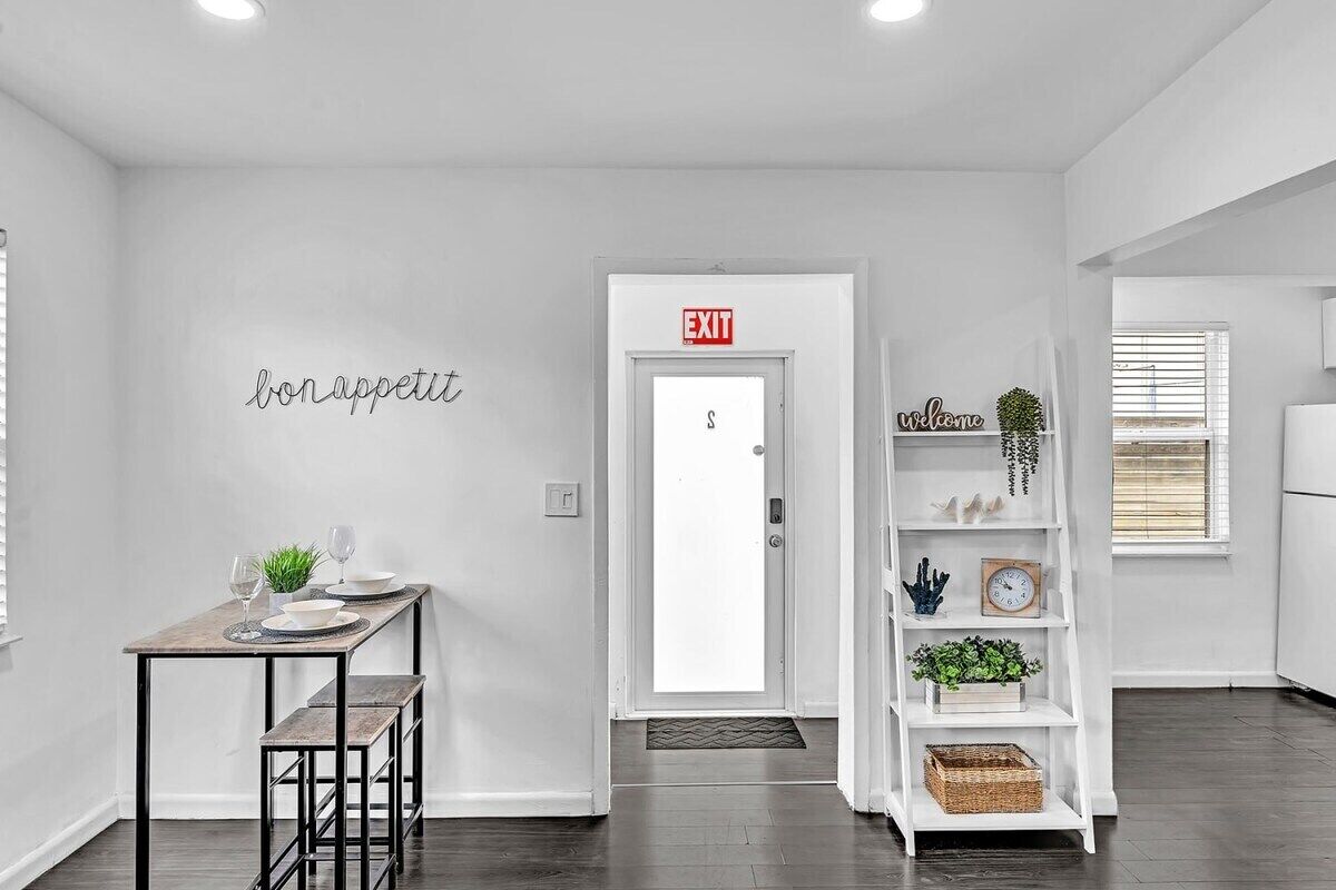 Un intérieur moderne comprenant un coin repas, un comptoir d’accueil blanc et un panneau d’accueil.
