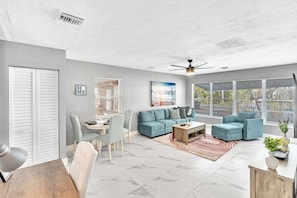 Relax in this inviting living room with a dining area, sofa, and coffee table, offering a view of the outdoors.