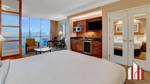 A hotel room with a large bed, a dining area with a table and chairs, a kitchenette, and a view of the city. - Strip View Studio | Jacuzzi, Pool & Kitchenette (Las Vegas)