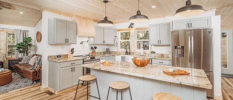 A modern kitchen with a large island, stainless steel appliances, and bar stools.
