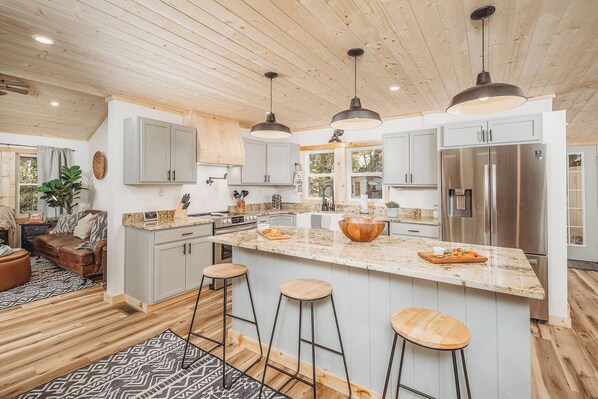 A modern kitchen with a large island, stainless steel appliances, and bar stools.