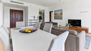 Een moderne woonkamer met een eethoek, een zithoek, een televisie en een schilderij aan de muur.