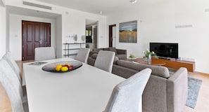 Ein modernes Wohnzimmer mit Essbereich, einer Sofagarnitur, einem Fernseher und einem Bild an der Wand.