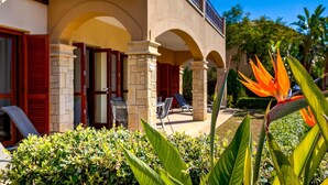 Een hotel met een overdekt terras, stenen zuilen en rode luiken.